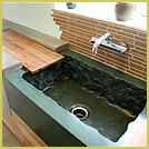 Concrete sink with rough edges and wooden drainboard